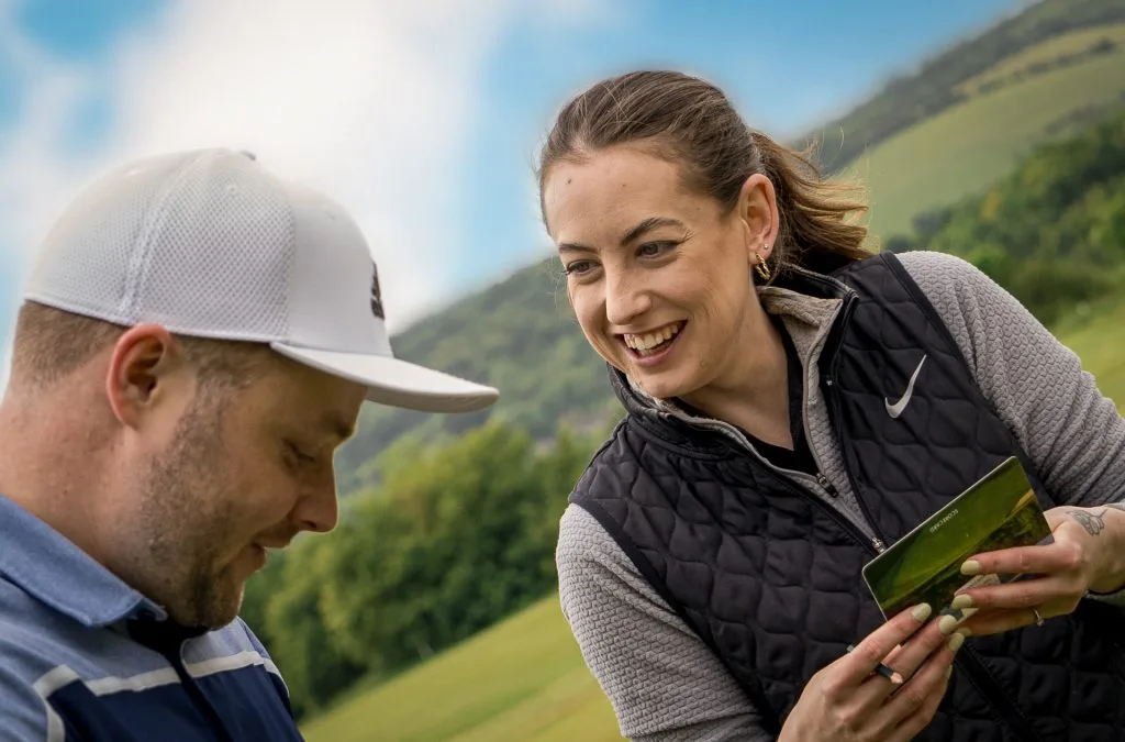 woman smiling at man holding scorehand at golf course in bristol