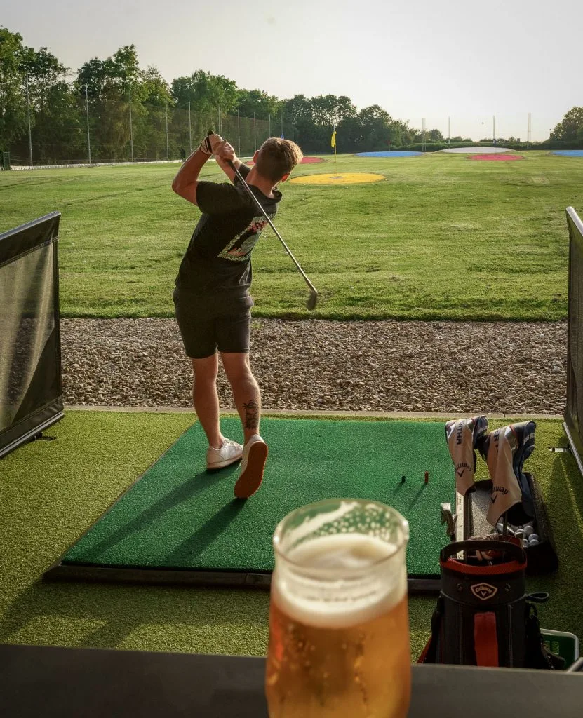 golf hitting out of bay at a driving range near bristol with the sun setting