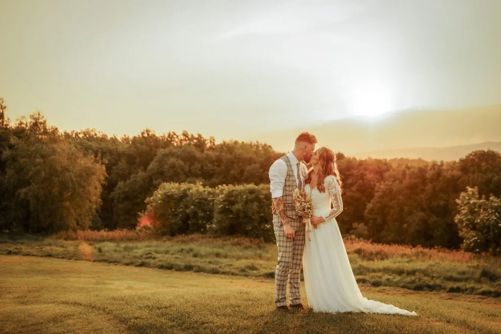 Couple standing on the golf course at Thornbury Golf and Lodge with a stunning sunset behind them – a romantic wedding venue near Bristol