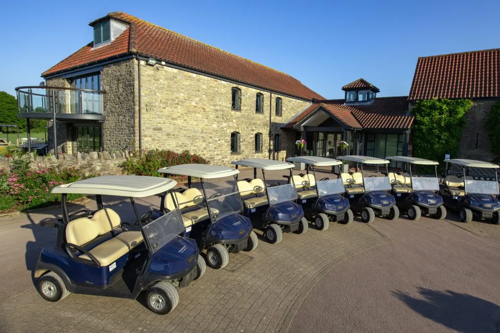 Fleet of golf buggies parked outside the clubhouse at a golf club in Bristol.