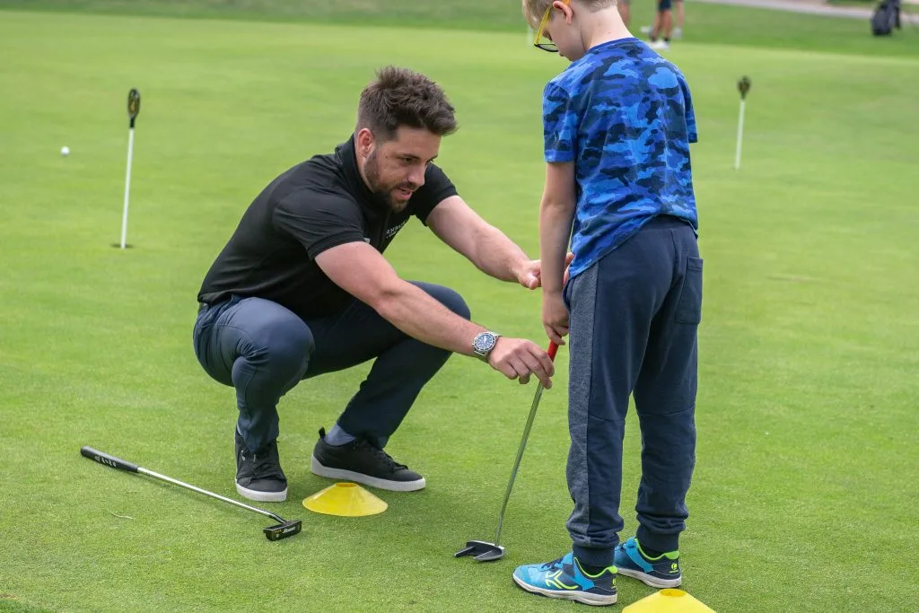 golf proffesional in bristol teaching young boy how to putt