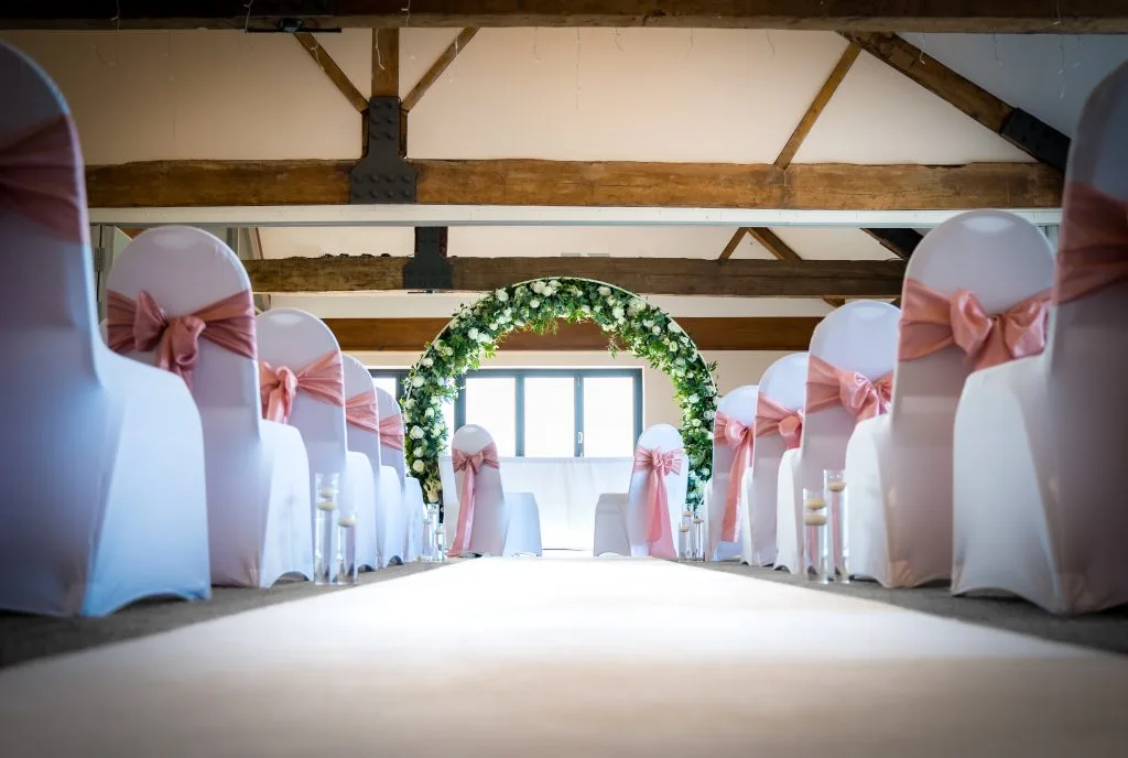 the wedding aisle at wedding venue in bristol with white chairs and flowery arch