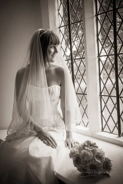 Bride sitting gracefully on the window sill of The Lodge Hotel in Alveston, a charming wedding venue near Bristol
